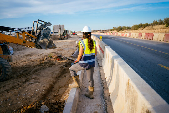Woman construction worker in hard hat at highway worksite