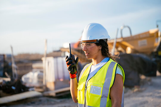 Female construction worker in helmet using radio on site