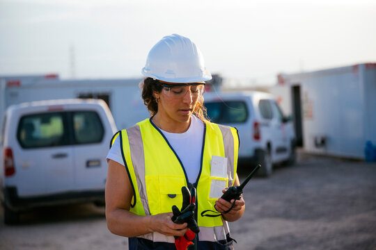 Woman construction worker in helmet using walkie talkie