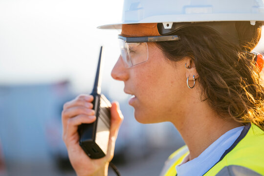 Woman construction worker using radio with helmet and PPE