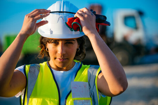Female construction worker adjusting helmet and glasses