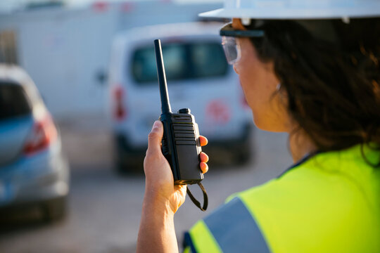 Woman construction worker using radio with safety helmet