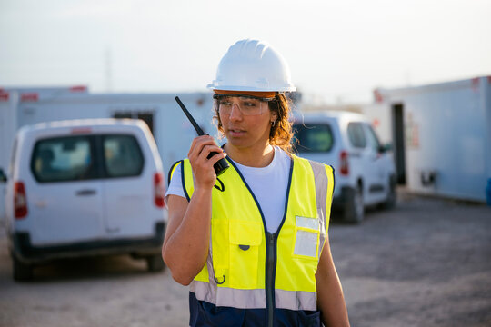Female construction worker using radio at site in hard hat