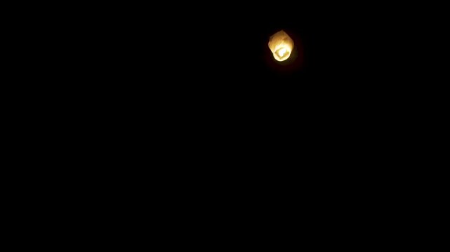 Lone glowing sky lantern in the night