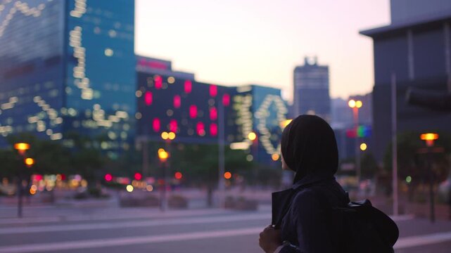 Thinking, student or Muslim woman in city at night for commute, study inspiration or view buildings. Evening reflection, smile or Arab person with hijab for education, travel or bokeh in urban town