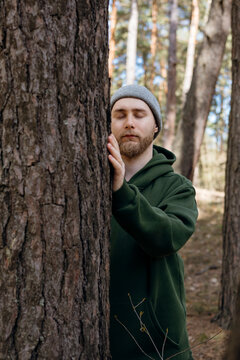 Mindful man touching pine tree in a quiet forest scene