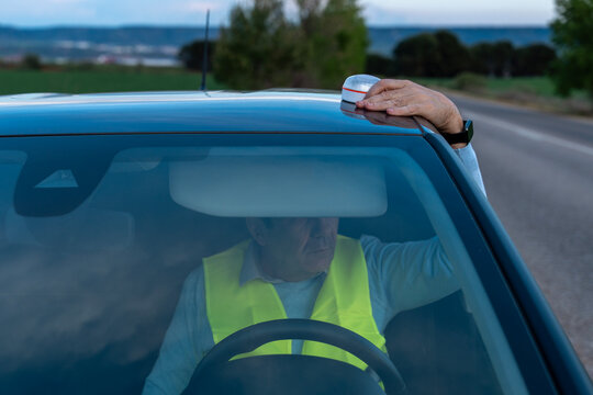 Driver placing V16 beacon on car roof for road warning