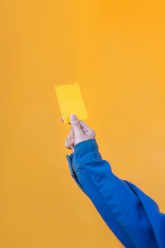 Young woman hand holding yellow card on colorful backdrop