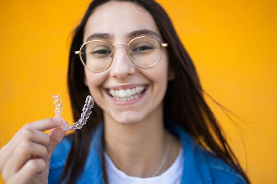 Young woman smiling with clear aligner on colorful background