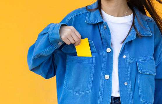 Young woman in blue jacket holding yellow card in pocket