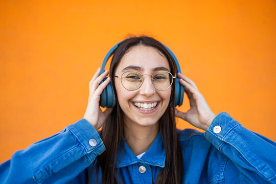 Young woman enjoying music with headphones on colorful backdrop