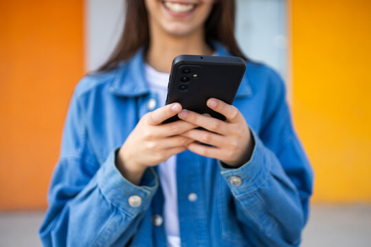 Young woman texting on smartphone against colorful background