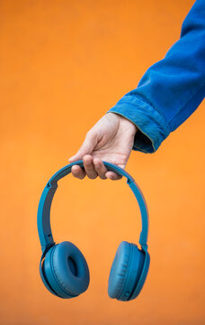Young woman holding wireless headphone on colorful background