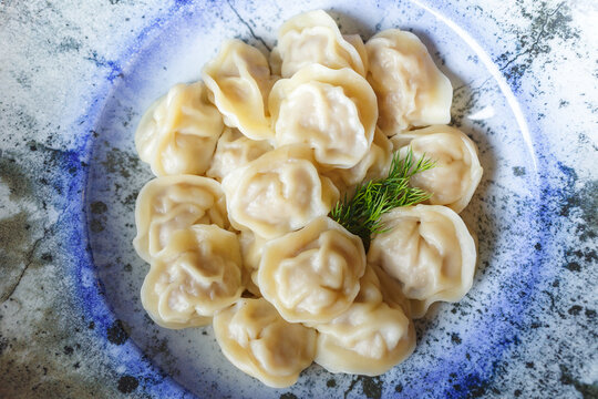 Traditional pelmeni on ceramic plate with dill garnish
