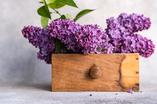 Lilac flower bouquet in wooden box on interior table setting
