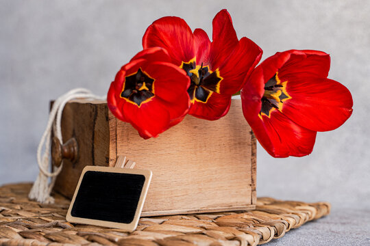 Red tulip bouquet in rustic interior with blank chalkboard