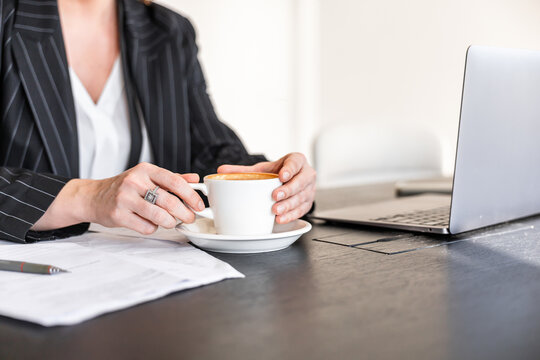 Woman in office holding coffee at her desk