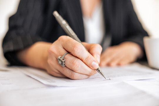 Woman writing with mechanical pencil in office setting