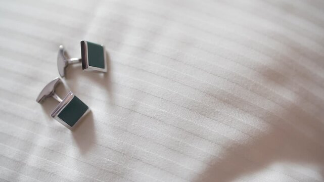 Pair of metallic cufflinks on pale textured fabric