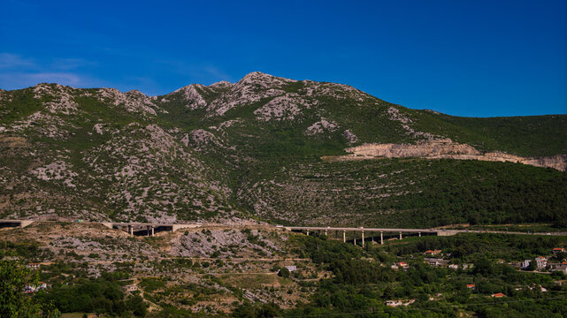Impressive highway viaduct bridge built along the steep rocky slopes of a green mountain, Klis, Croatia.