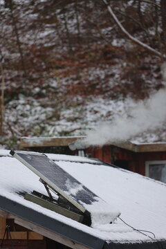 Snow-covered roof with solar panel in winter landscape