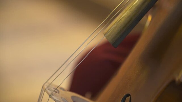 Hand playing bowed string instrument in warm light
