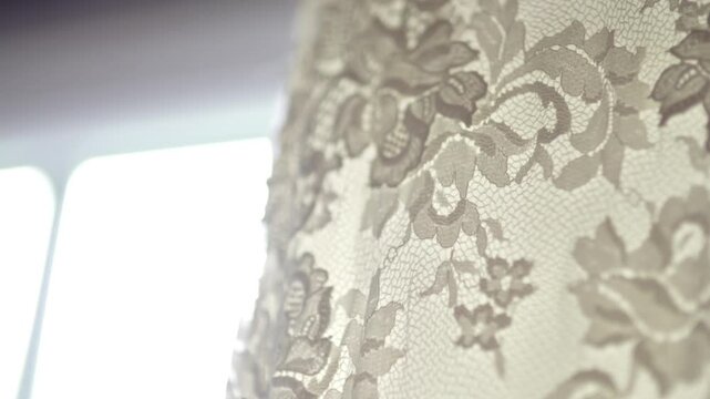 Delicate floral lace fabric hanging near a bright window