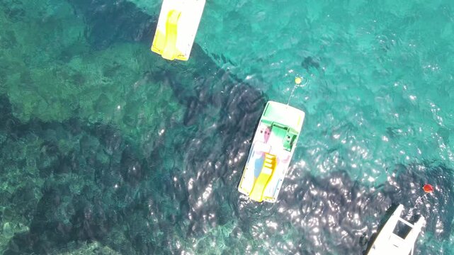 Colourful Pedal Boat on the shoreline. Overhead aerial view from drone. Slow motion