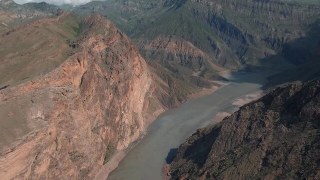 Aerial view of the confluence of the Avar Koysu and Andi Koysu rivers flowing through a deep mountain canyon in Dagestan, Russia, dramatic cliffs and clouds