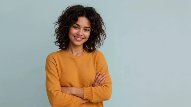 Happy young woman with curly hair smiling with arms crossed