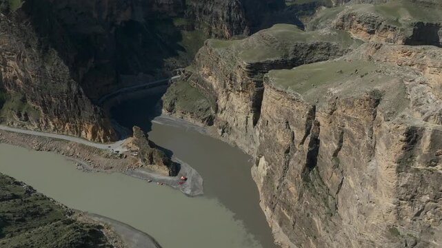 Drone footage of the confluence of the Avar Koysu and Andi Koysu rivers in a deep mountain gorge, Dagestan, Russia, with winding road and rocky cliffs