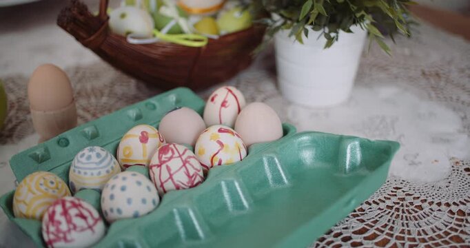 Decorated Easter eggs in a green carton on a lace table