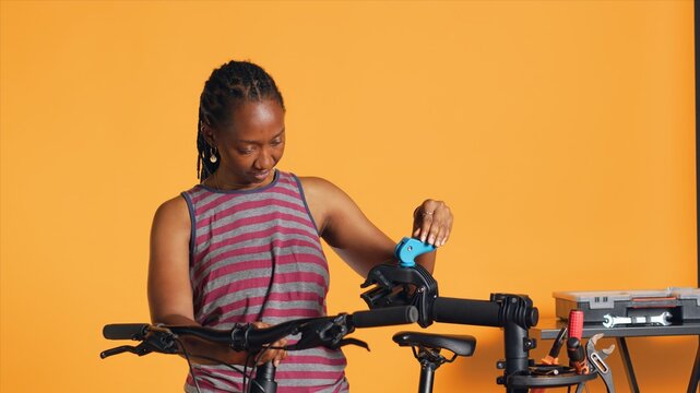 Engineer setting up bike repair stand, using it to adjust derailleur and cables, fixing broken wheels, studio background. Professional assembling workstand to maintain bicycle at eye level, camera A