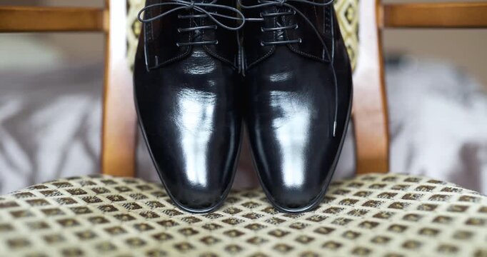 Polished black dress shoes resting on upholstered chair