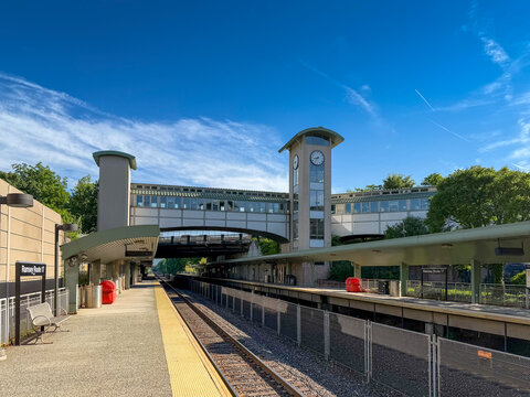 Ramsey, NJ - US - Jun 5, 2026 The Ramsey Rt. 17 station has pedestrian overpass, a clock tower, covered platforms walkways, surrounding green trees, and a blue sky with light clouds.