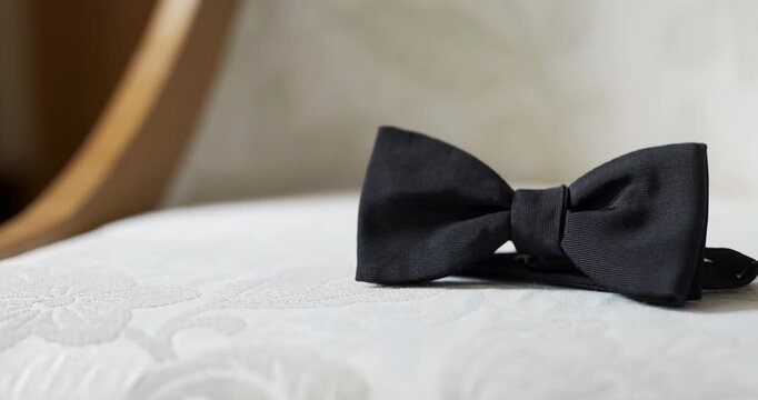 Black bow tie on white pillow in soft interior light