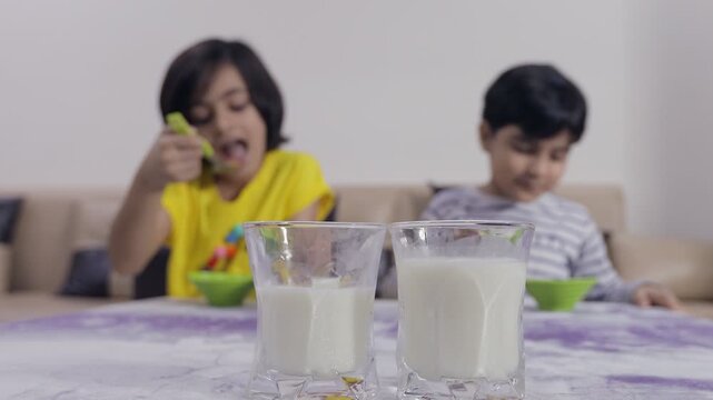 Adorable little siblings playfully teasing each other while having their breakfast. Happy Indian brother and sister cheerfully eating their morning meal while irritating one another - lifestyle kids