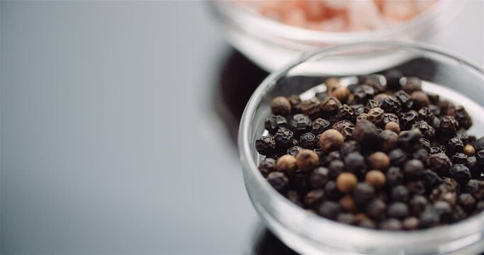 Close-up glass bowl of peppercorns on gray surface