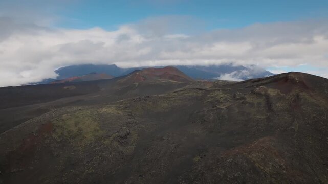 Drone footage of volcanic cinder cone and black lava fields at Northern Breakthrough in Tolbachinsky Dol, Kamchatka Krai, Russia under low clouds