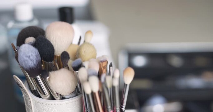 Makeup brushes standing in a white cup on a vanity table