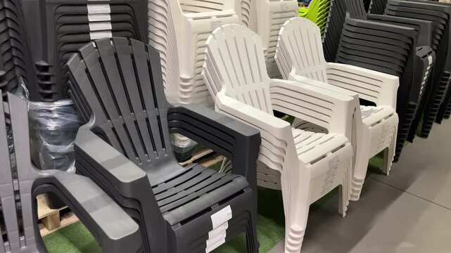 Stacked Plastic Garden Chairs on Display in Retail Store &mdash; Slow Motion Tracking Shot | White and Dark Gray Adirondack Style Outdoor Seating in Furniture Showroom