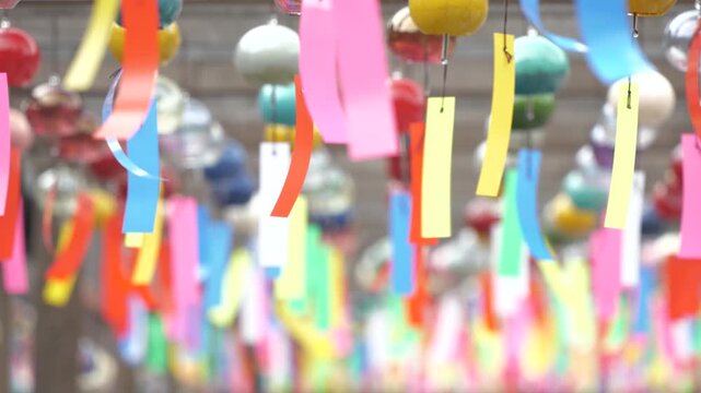 夏の風物詩として、多数の色とりどりの風鈴が揺れる涼しげで華やかな光景
