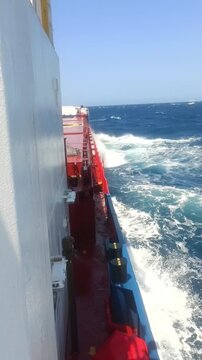 Vertical shot of a ship deck with a slow motion wave splash crashing at the end.