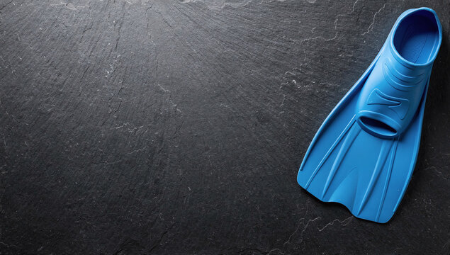 Single blue swim fin aligned on dark slate surface background