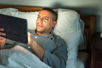 Fototapeta premium Man reading tablet in bed.