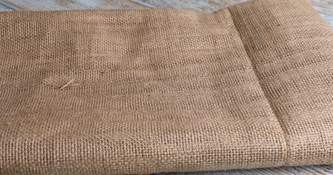 Woman putting folded burlap fabrics onto wooden table, closeup