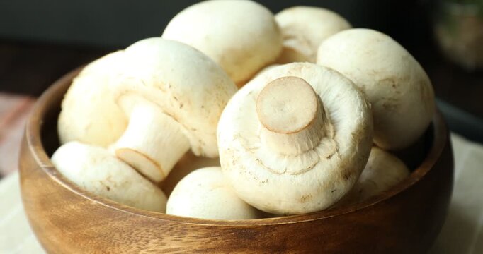 Fresh champignon mushrooms in bowl on table, rotating