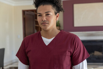 Obraz premium Mid adult man standing in living room wearing maroon scrub top with chest pocket