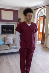 Obraz premium Man wearing maroon scrubs with white shirt standing hands in pockets in living room near door