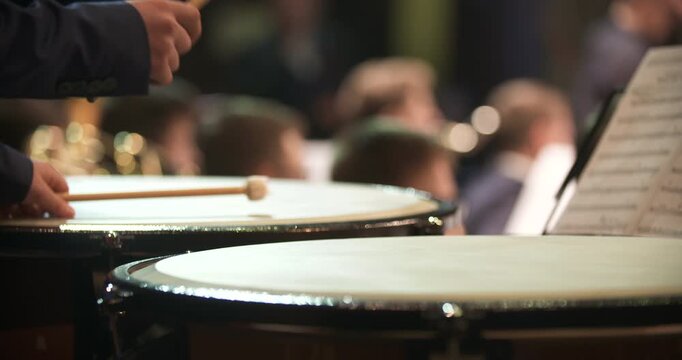 Percussionist striking a concert drum during an orchestra performance